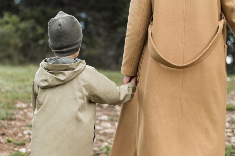 Back view woman holding her child by the hand. Fotó: Freepik