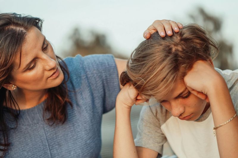 Woman in Blue Shirt Talking to a Young Man in White Shirt